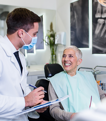 Senior dental patient smiling at her dentist