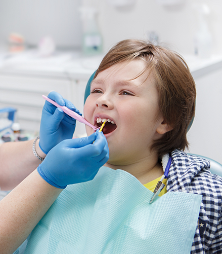 Child in dental chair having fluoride applied to their teeth