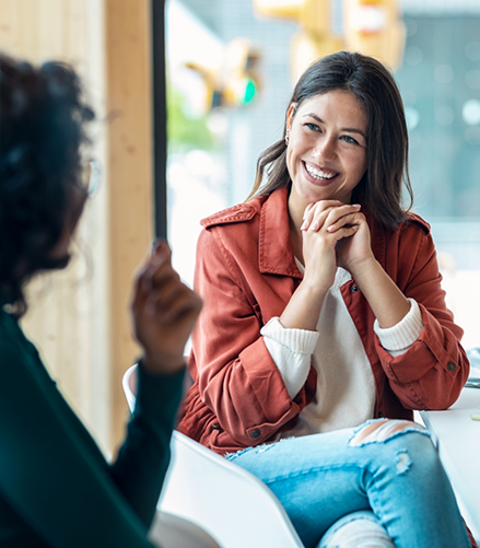 Two women smiling and sitting across from each other