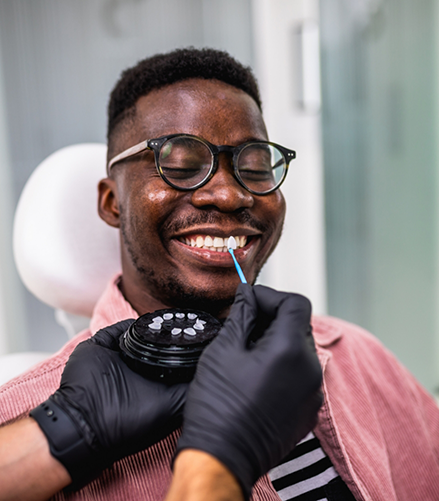 Dentist holding a veneer to a patients smile