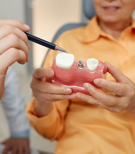 Dentist showing a model of a dental implant to a patient