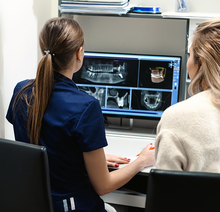 Dentist showing a patient x rays of their teeth on a computer screen