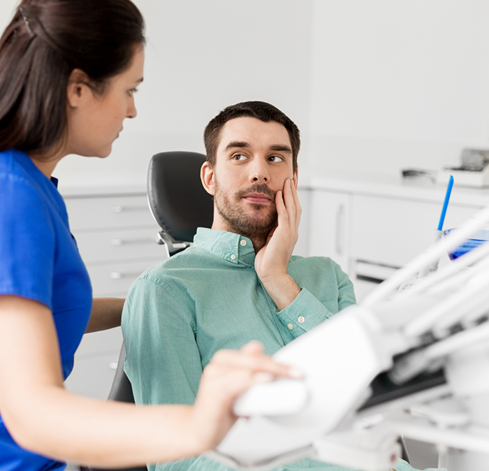 Man holding his cheek in pain while talking to emergency dentist in Independence