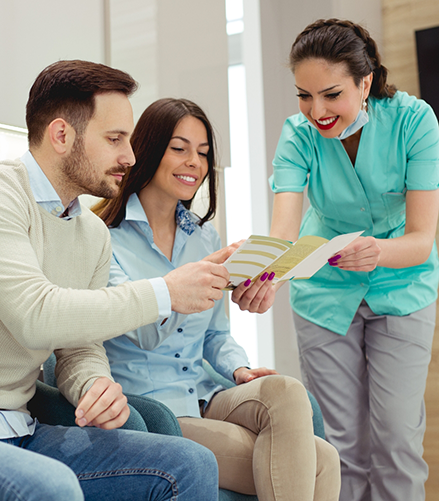 Dental team member showing a pamphlet to two patients