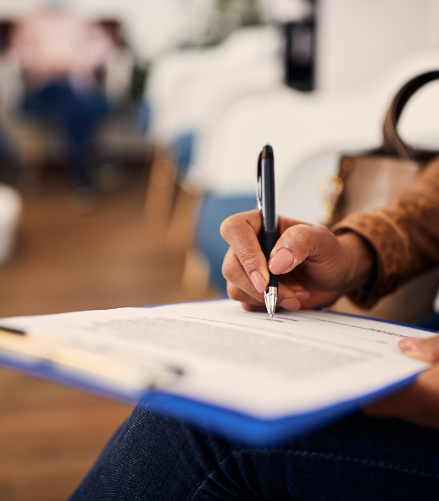 Person filling out paperwork on a clipboard