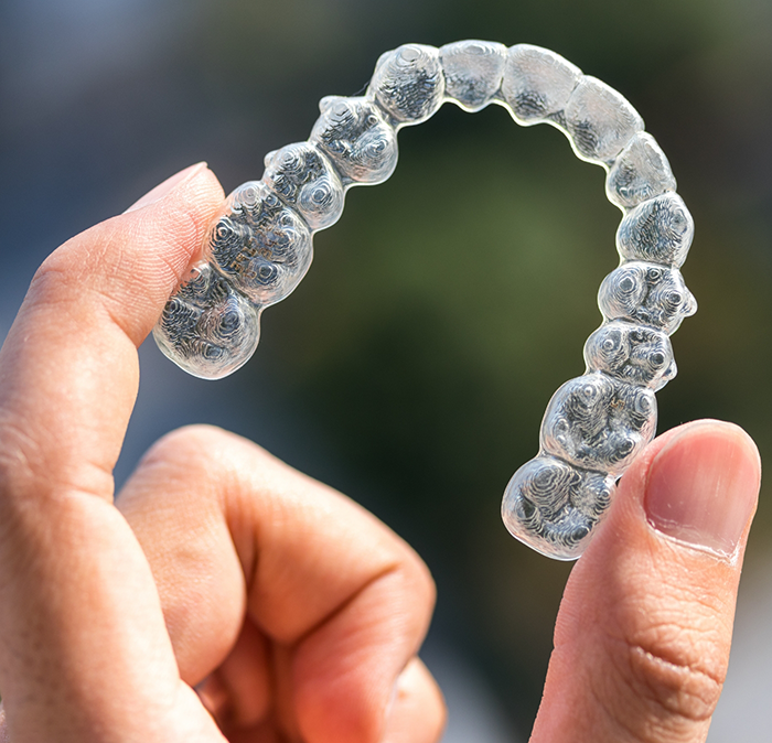 Hand holding an Invisalign clear aligner in Independence