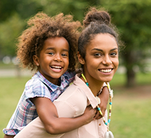 Smiling mother giving her daughter a piggyback ride