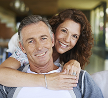 Smiling woman hugging a smiling man from behind