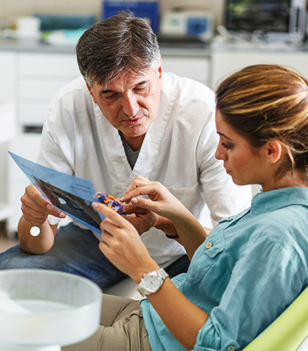 Dentist showing a dental appliance to a patient in the treatment chair