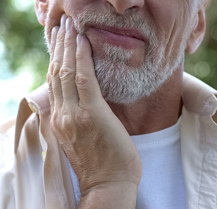 Man holding his cheek in pain before root canal treatment in Independence